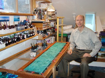 Silk artist Warren Hartz in his studio with a silk scarf stretched on a frame.